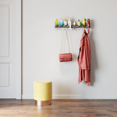 Bunte Garderobe mit Vogelpärchen Wandhaken: Die farbenfrohen Vogel-Wandhaken halten einen pinken Mantel und eine Tasche, während ein gelber Hocker den Endless-Summer-Feeling-Look auf dem Holzfußboden abrundet.