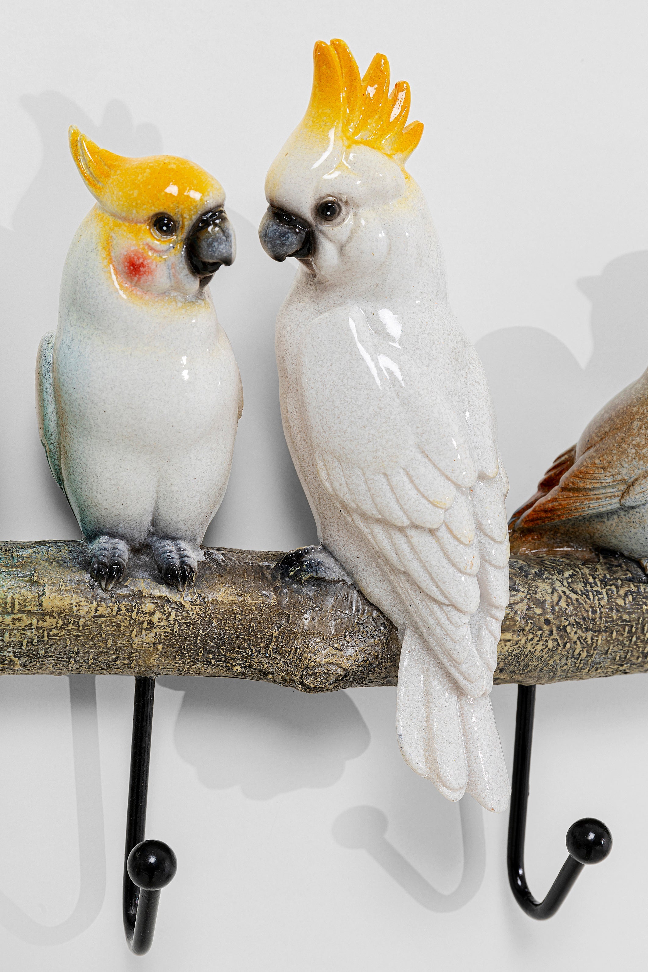 Zwei Keramikkakadus mit gelbem Kamm sitzen auf einem Vogelpärchen-Wandhaken in Form eines Astes und bringen Endless-Summer-Feeling und Farbe in jede bunte Garderobe.
