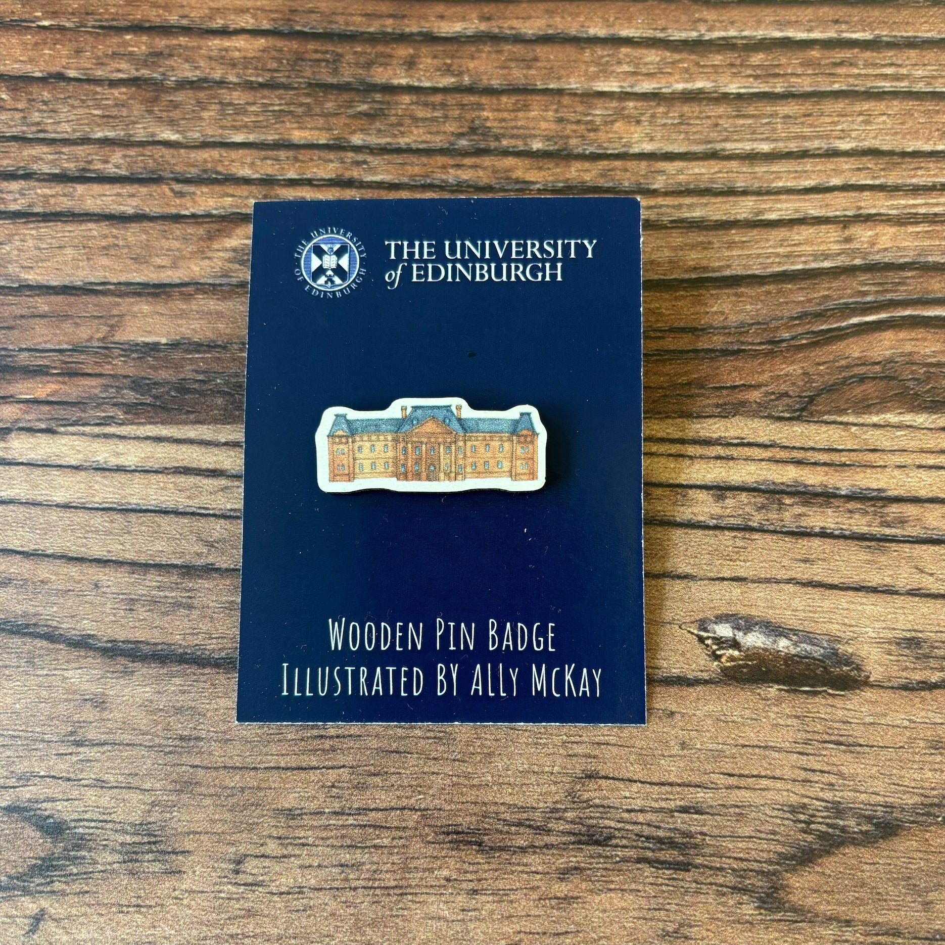 The Edinburgh College of Art wooden pin badge on its backing card.